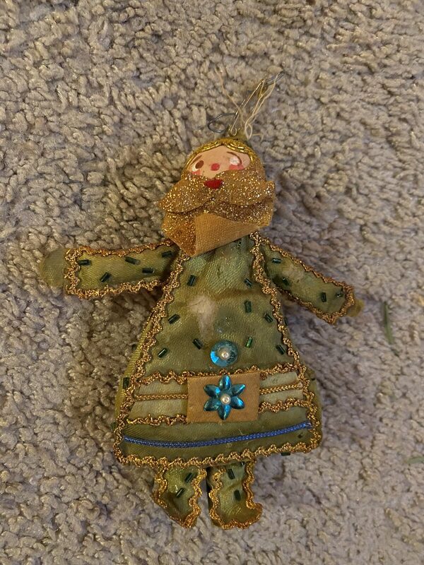A folk fabric figure with a spun-cotton-style head, green felt gown and gold trim